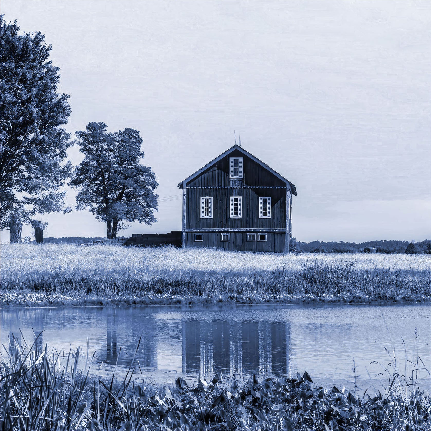 Artwork of a barn and tree beside water in tranquil blue tones, reflecting in the calm waters with a serene countryside landscape and peaceful ambiance.